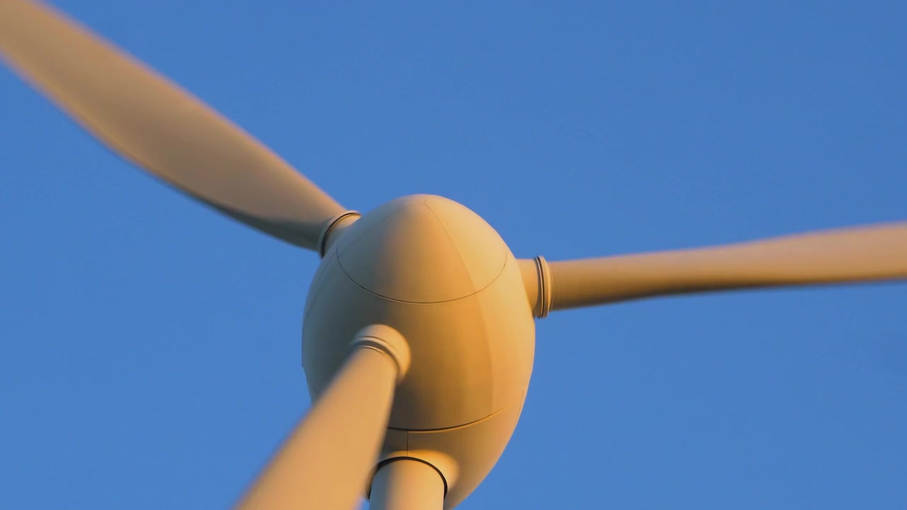 Splendida vista di una turbina eolica che genera energia rinnovabile in un parco eolico, paesaggio di campagna verde, vibrante serata primaverile soleggiata con la luce dell'ora d'oro, ripresa in primo piano