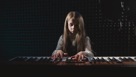 child tinkers with piano keys at music lesson. petite artist explores intricacies of musical device within confines of sound recording studio