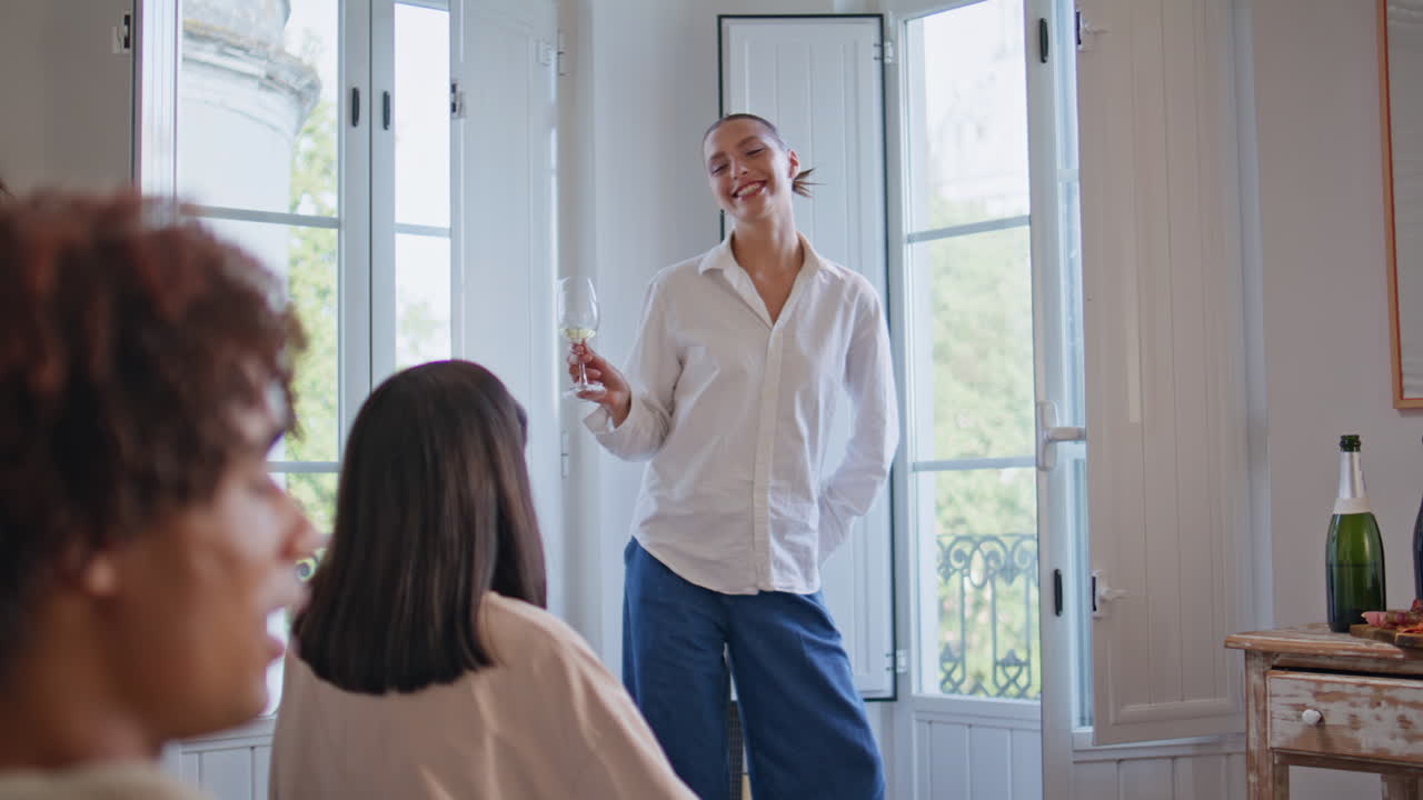 Laughing girl holding wineglass talking mates at room. Friends sitting together