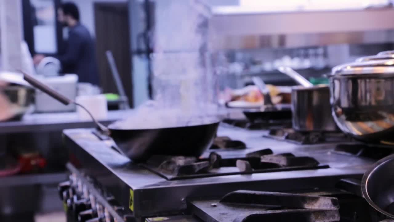 シェフが鍋で燃える火で肉を調理する