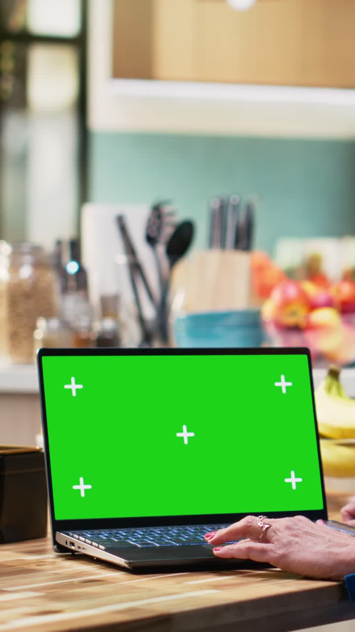 Vertical Video Chroma key laptop with elderly woman sitting at the breakfast table