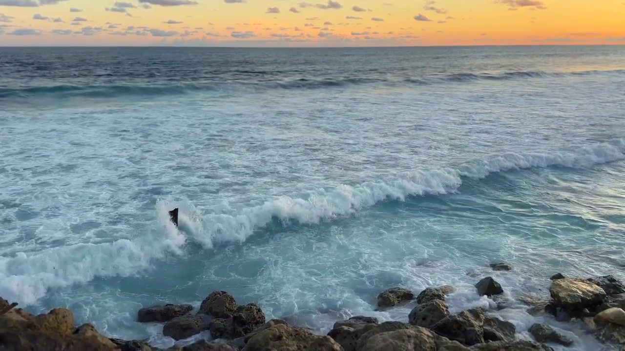 Le onde dell'oceano si schiantano contro la costa rocciosa al tramonto