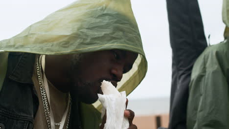 man eating burrito on the beach