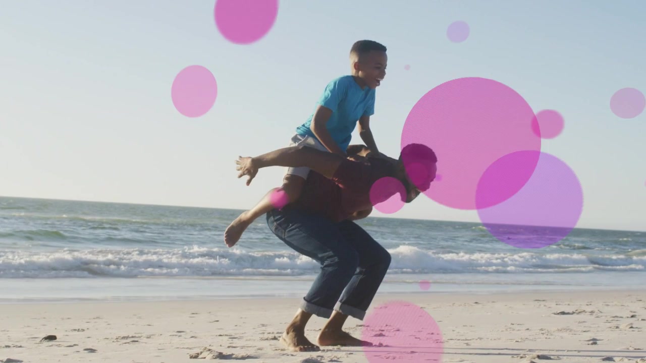 Son running to dad on shore, jumping on back, dad lifting pink-purple bubbles growing around family