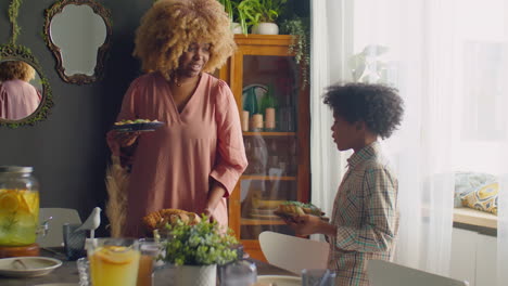 mother and little son setting up table for family dinner