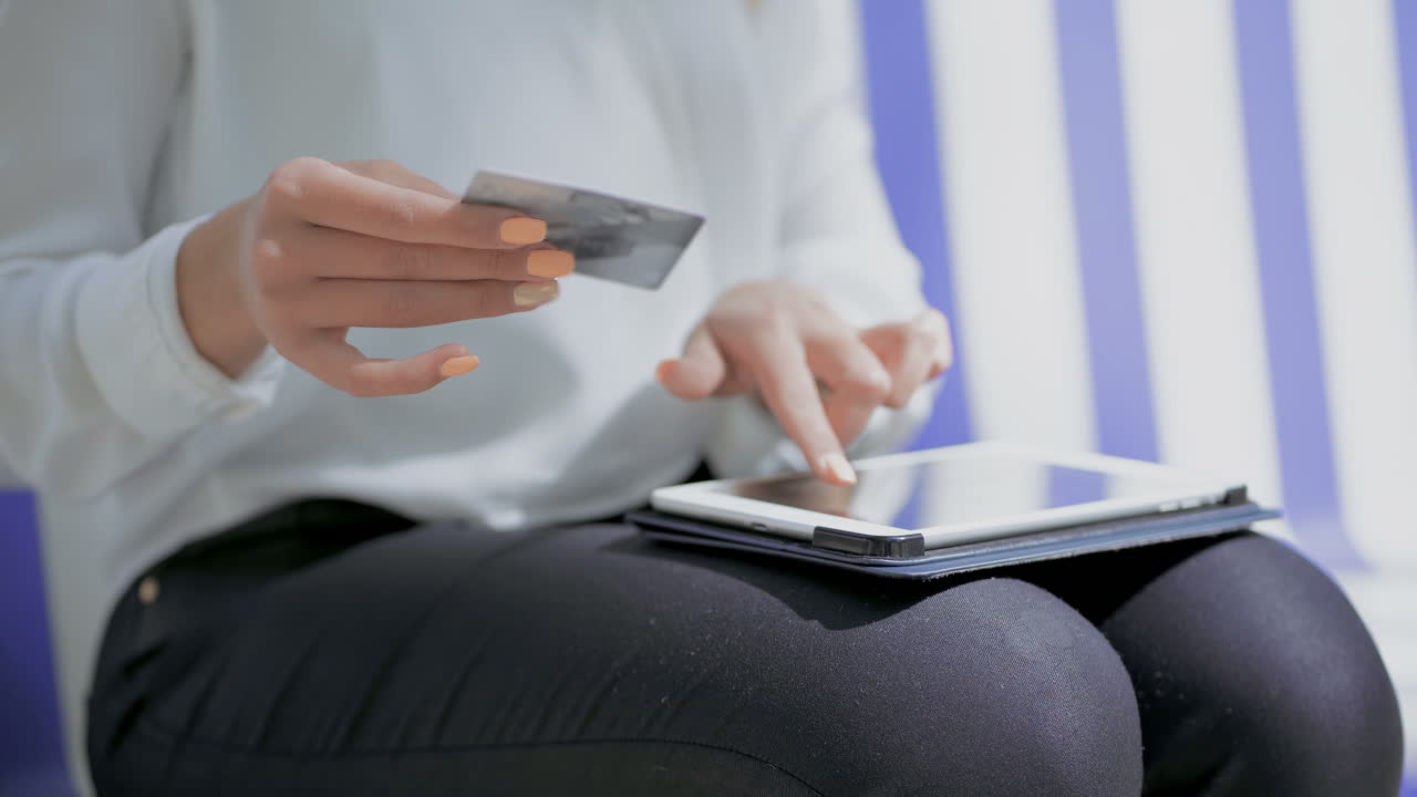 Ragazza che tiene una carta di credito e usa un tablet