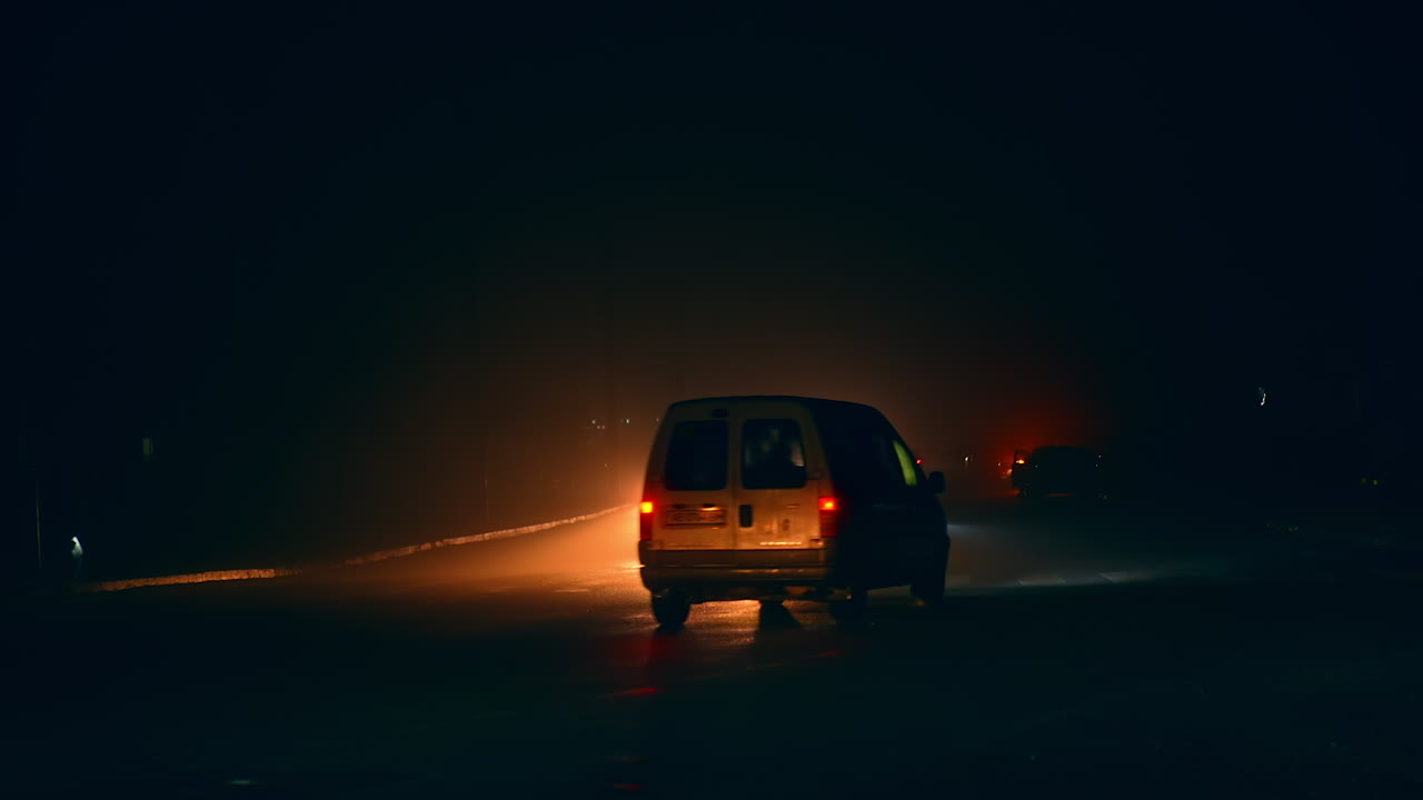 Cars driving in foggy weather at night