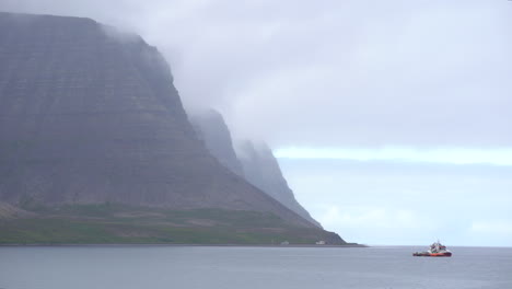 Kleines-Boot,-Das-Auf-Ruhigem-Meer-Mit-Berglandschaft-Schwimmt