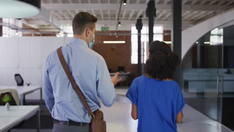 hombres y mujeres de negocios de diversas razas caminando discutiendo por el pasillo con máscara facial