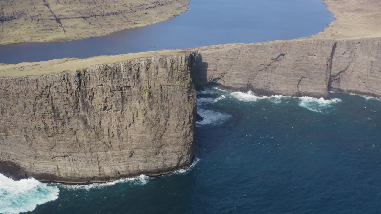 Aerial view of waves crashing against gigantic Tr&aelig;lanipa cliffs on Vagar - Faroes Islands