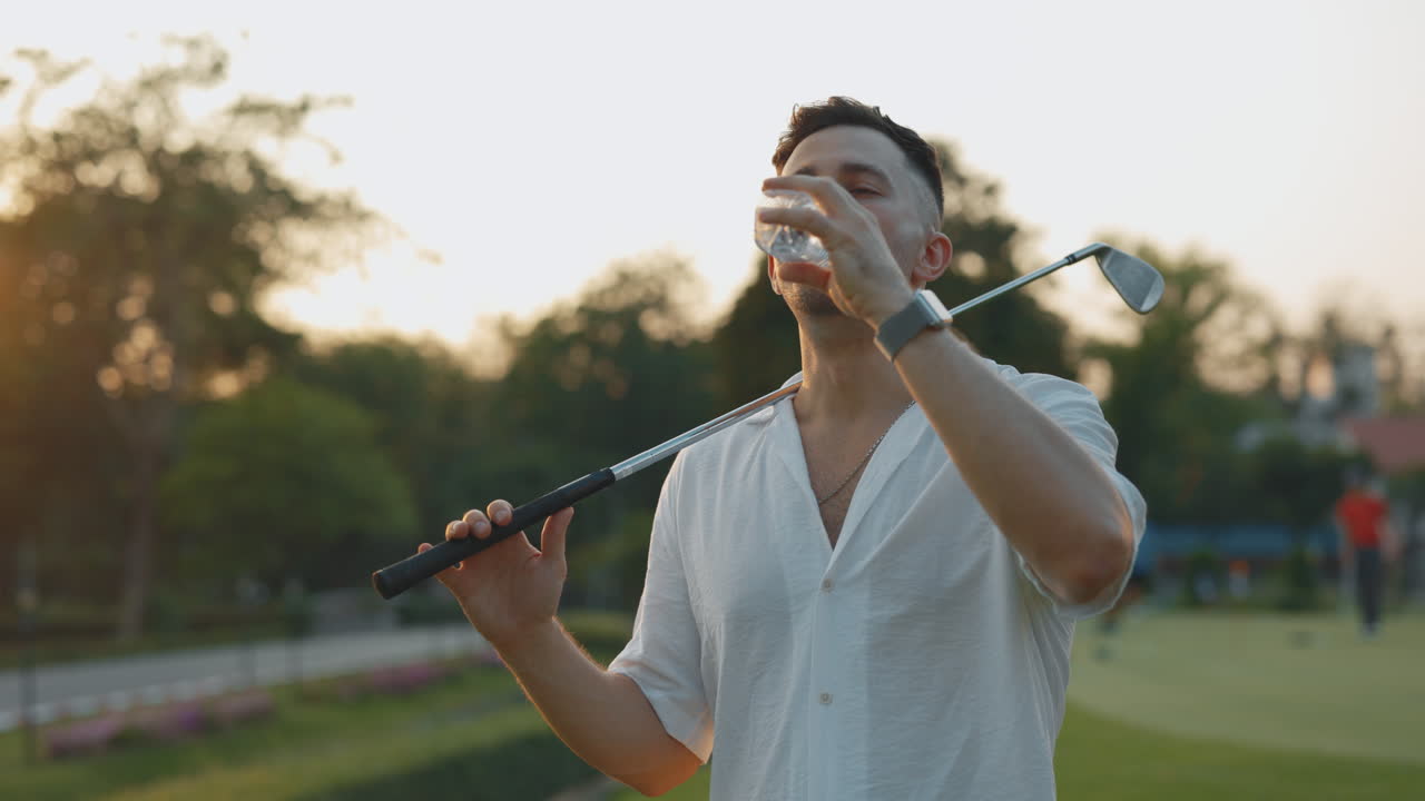 Golfer Drinking Water on the Course During Sunset