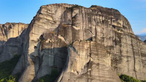 Vista-Ascendente-Contra-Una-Enorme-Pared-De-Arenisca-En-Meteora,-Grecia,-Antena