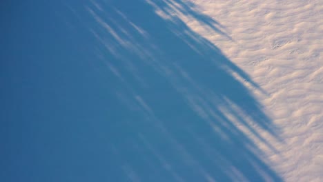 Top-Down-Luft,-Die-Langsam-Vorwärts-über-Schatten-Und-Muster-Im-Frischen-Schnee-Fliegt