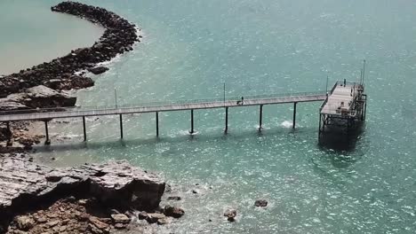 Flying-over-Darwin-beach-pier-nearby-rocky-cliffs