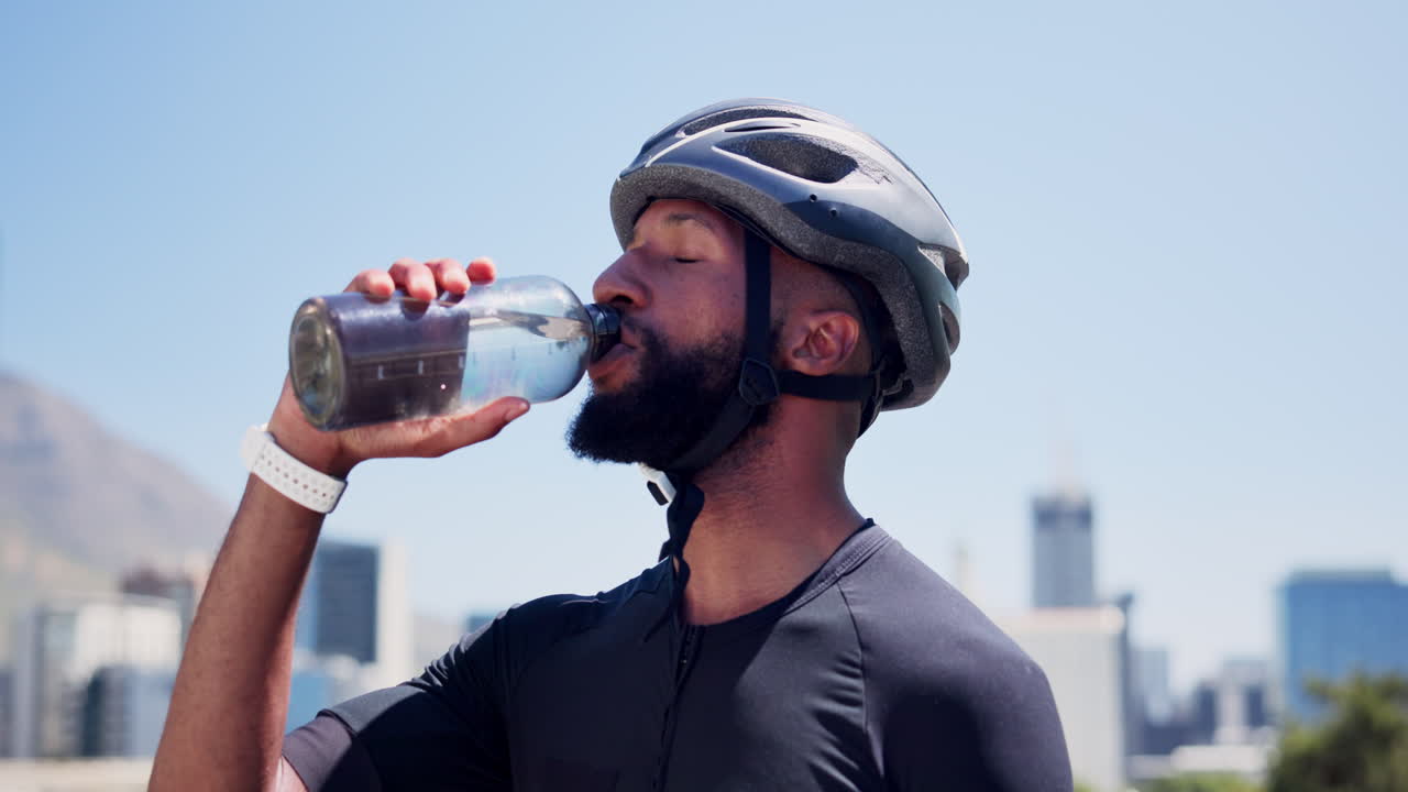 Cyclist Man Drinking Water from Bottle Outdoors in City