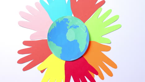 close-up van handen samen met een globe gemaakt van kleurrijk papier op een witte achtergrond met kopieerruimte