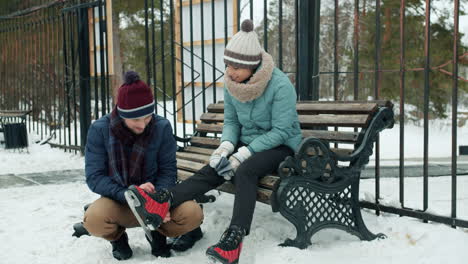 couple putting on skates in winter park