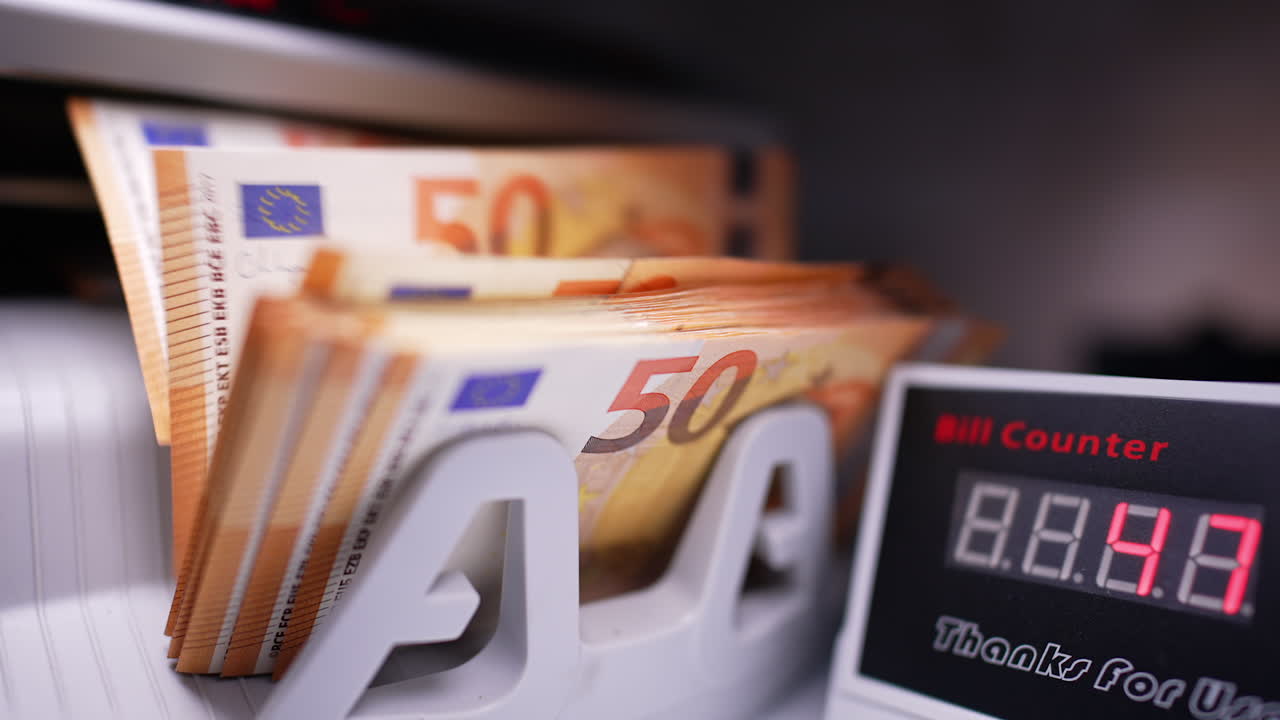 Counting fifty euro bills in bank device. Display of cash counting machine shows changing numbers. Close up. Blurred backdrop.
