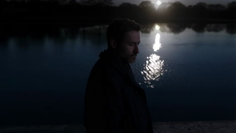 a man standing by a lake at night