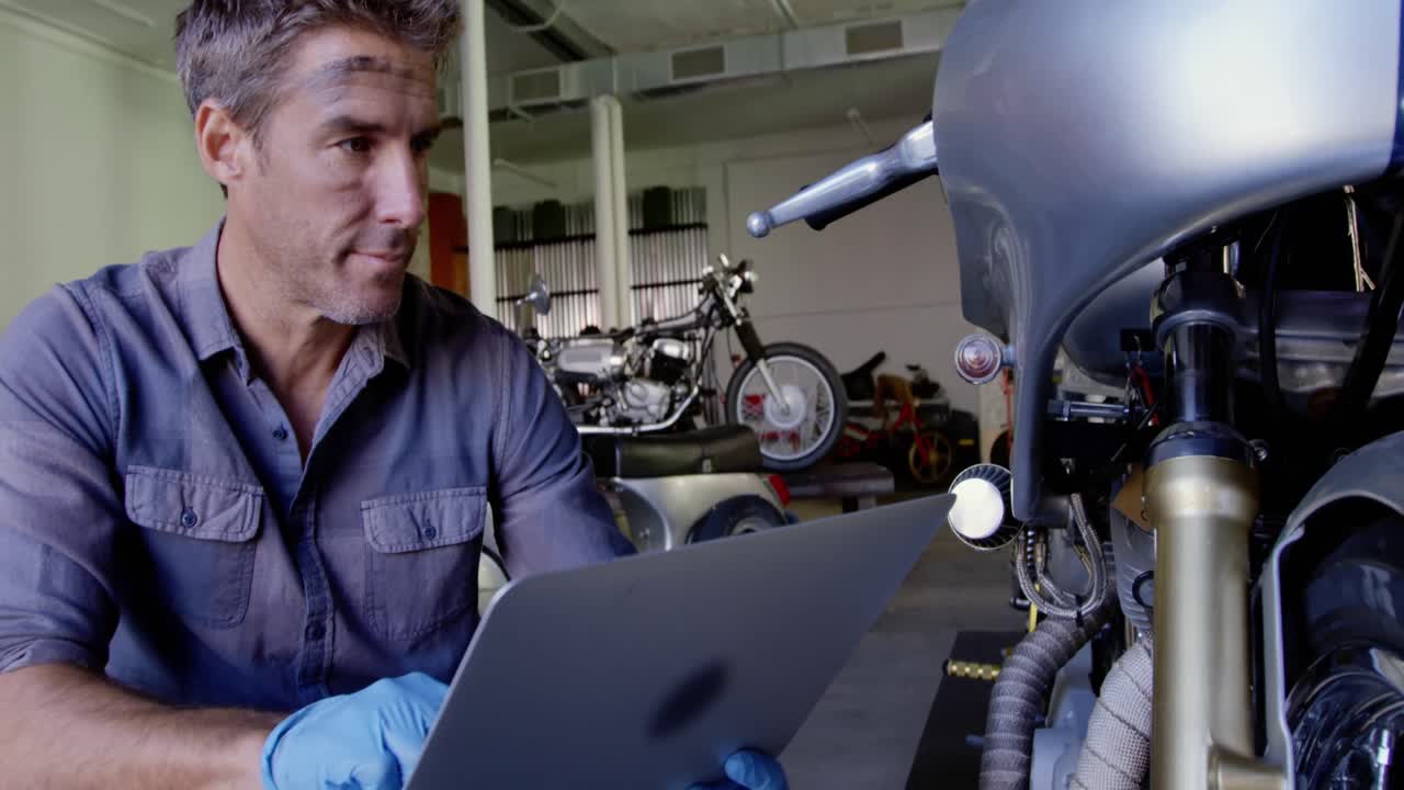mecánico masculino usando una computadora portátil en un garaje de reparación de motocicletas 4k
