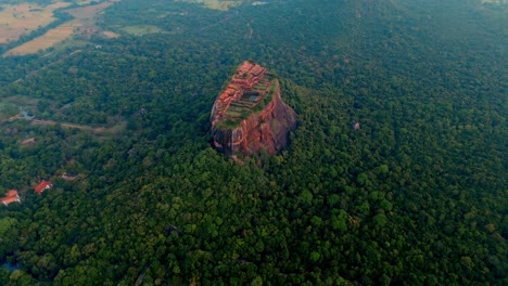 aerial footage showcasing the iconic sigiriya rock fortress rising dramatically above the surrounding jungle in central sri lanka.