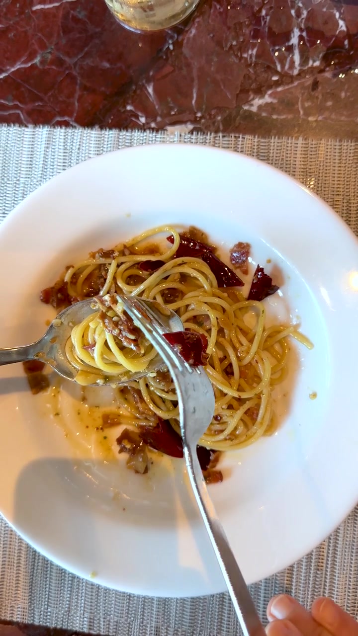 Ripresa dall'alto di mani che arrotolano spaghetti piccanti con forchetta e cucchiaio a pranzo.