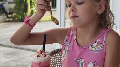 una chica comiendo un batido de fresa.