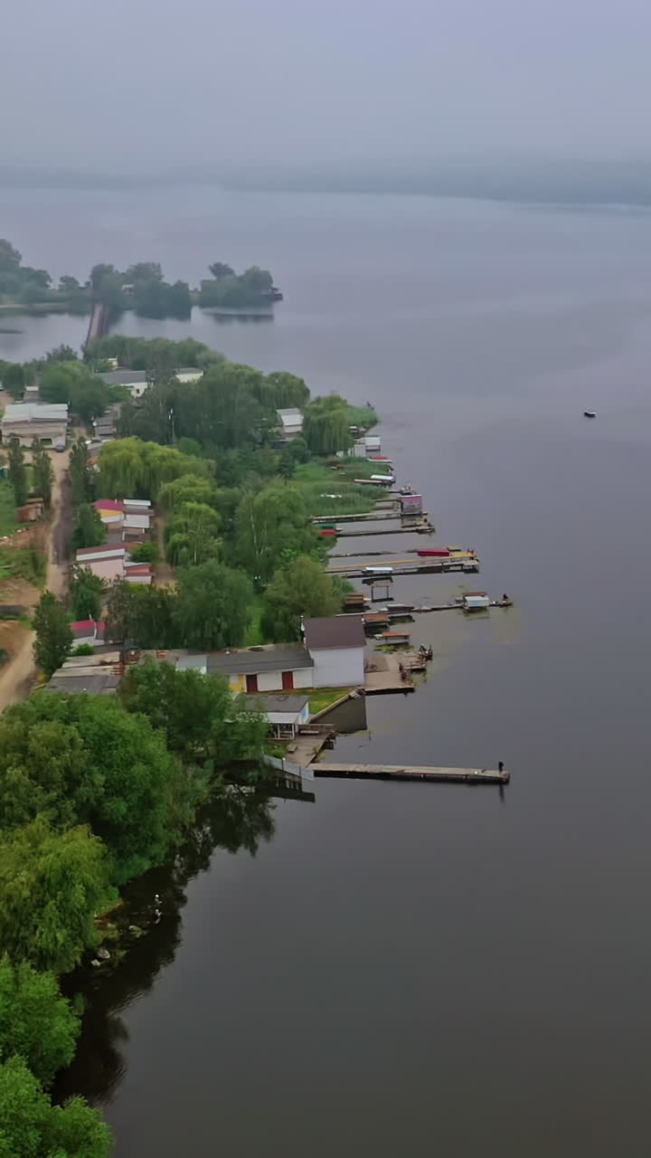 High voltage lines near the river. Electric towers in the countryside on water background. Power transmission lines in nature. Aerial view. Vertical video
