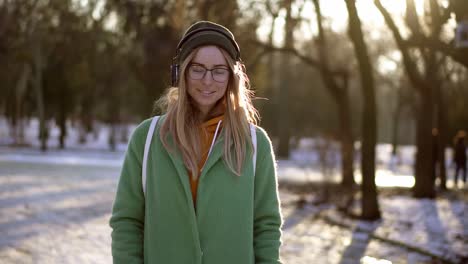 carefree girl walk in winter park, listening to music on the phone in a good mood