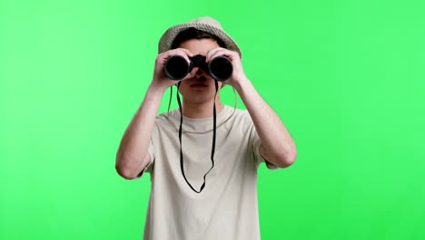 young man explorer in hat looking through binoculars