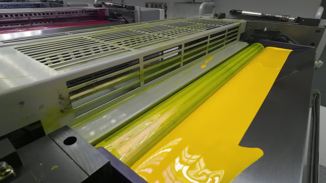 Zoom out of a printing press roller covered in vibrant yellow ink