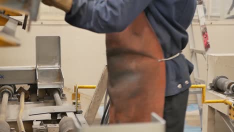 factory worker assembling metal parts on assembly line