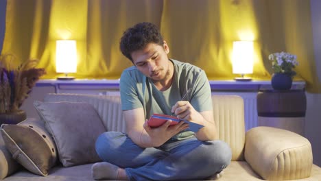 happy man at home at night keeping a diary. man both thinks and writes.