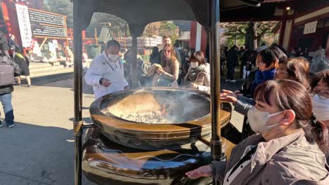 visitors partake in incense smoke ritual outdoors