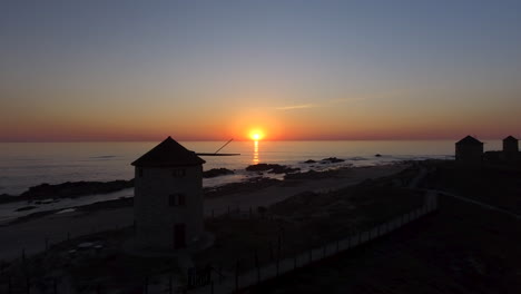 toma aérea panorámica de 4k de molinos de viento cerca de la costa del mar que revela una hermosa puesta de sol