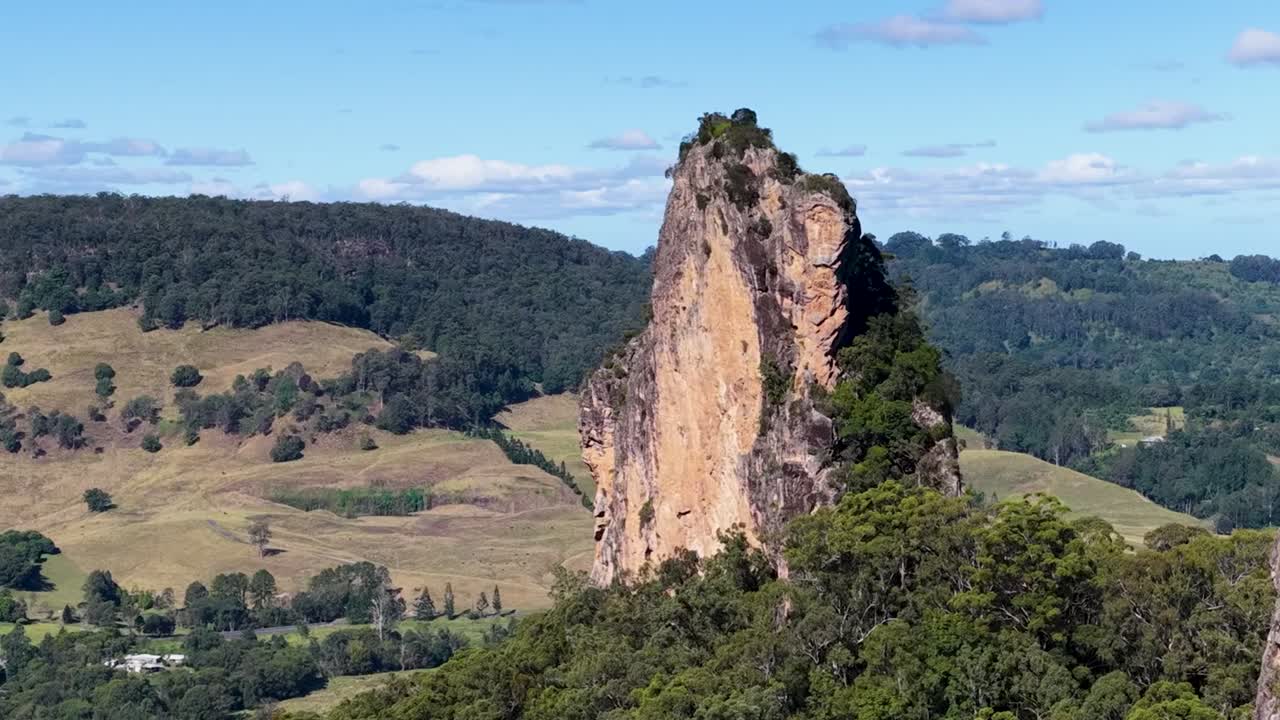 Drammatiche guglie rocciose verticali si ergono imponenti su una valle verdeggiante sotto un cielo azzurro e limpido.