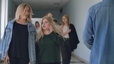 A-group-of-students-walk-along-the-corridor-of-the-university-school-college-communicate-talk-and-smile.-A-large-group-of-people-walking-in-the-hall-of-an-educational-institution-with-books-in-their-hands.