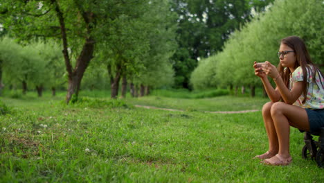 Teenager-Mädchen-Sitzt-Auf-Kinderwagen-Mit-Telefon.-Mädchen-Benutzt-Smartphone-Im-Park.