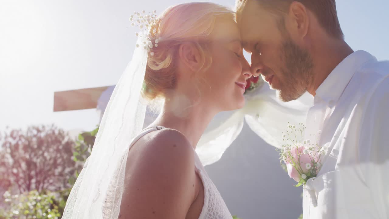 Happy caucasian newly wed couple, standing touching heads at altar outdoors