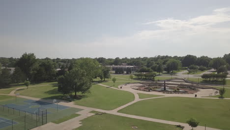 Aerial-pushing-out-shot-revealing-a-stunning-water-fountain-and-a-kids-play-park