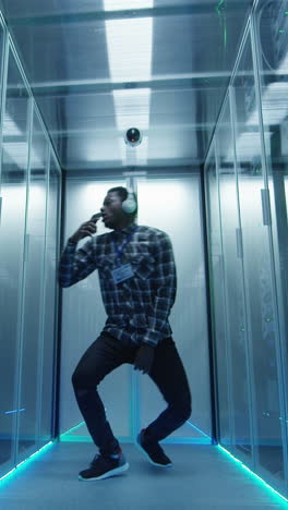 Man dancing and working with headphones in a modern data center