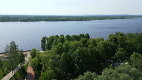 Aerial view of a wide river with green trees and a park on the bank