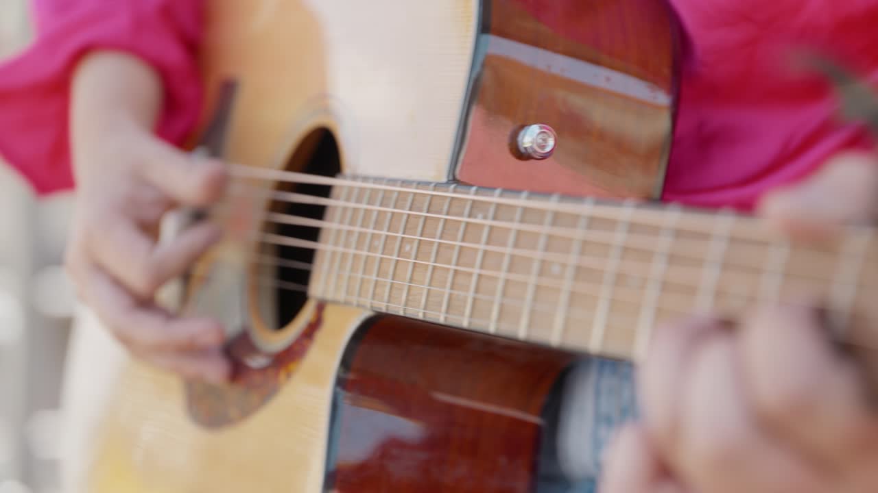 Primer plano de una persona tocando música country en una guitarra acústica en un festival de música en el interior.