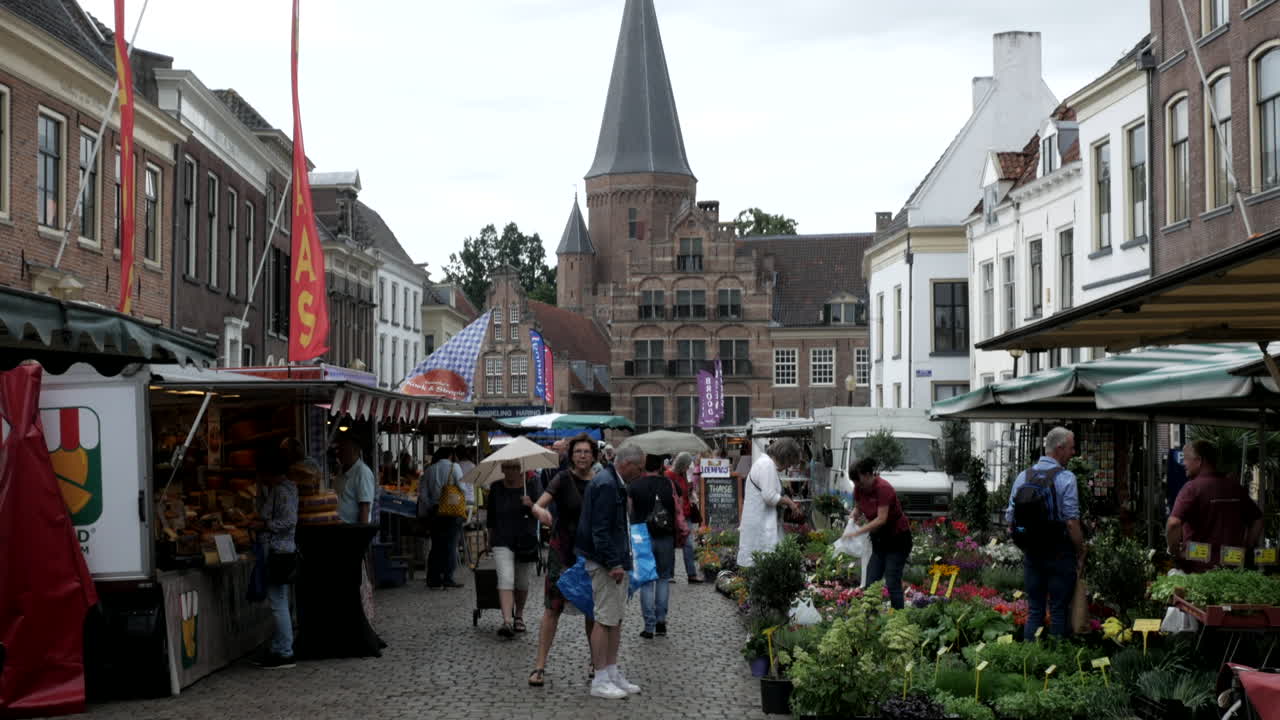 People walking on road at street market in Netherlands on cloudy day. 4K