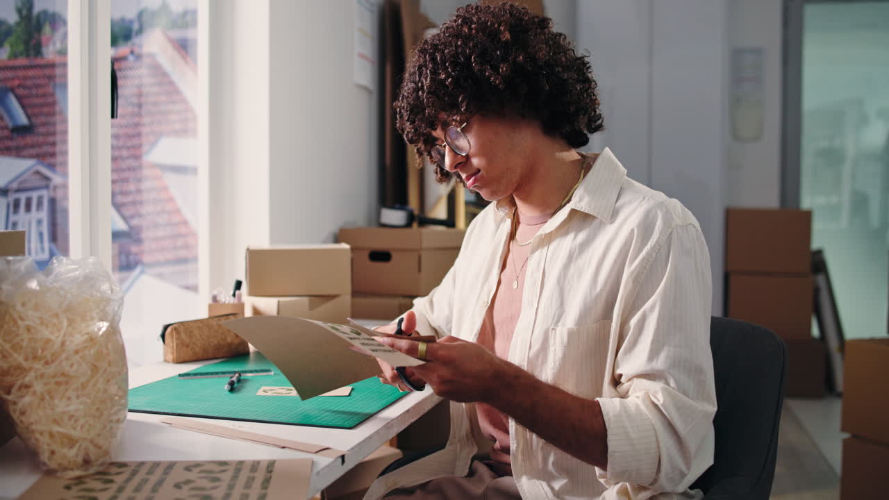 Young Man Cutting Eco-Friendly Packaging in a Small Business Workspace