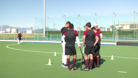 male hockey team huddling on field, discussing strategy during practice session
