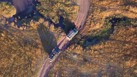 safari vehicles driving off-road in kenya, africa on a sunny day
