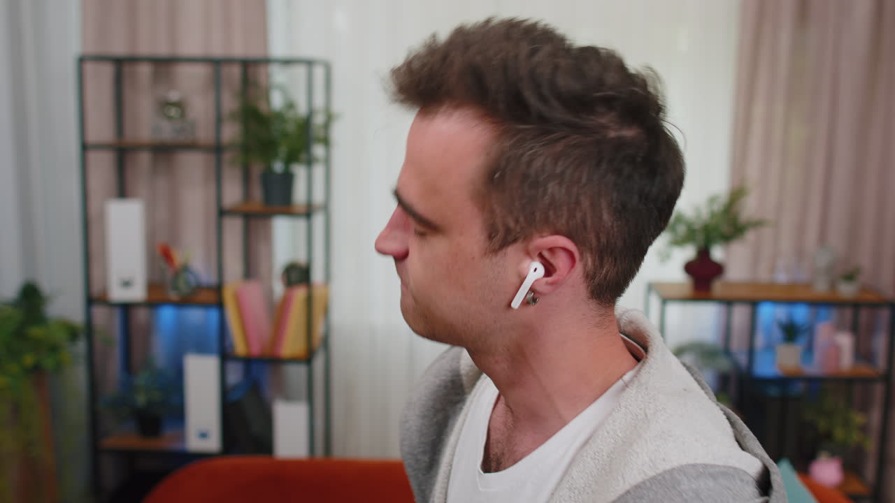 hombre feliz y relajado con auriculares inalámbricos bailando, escuchando su música rock n roll favorita en casa