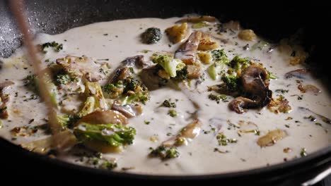 cooking and stirring milk with mushroom, cauliflower, and broccoli