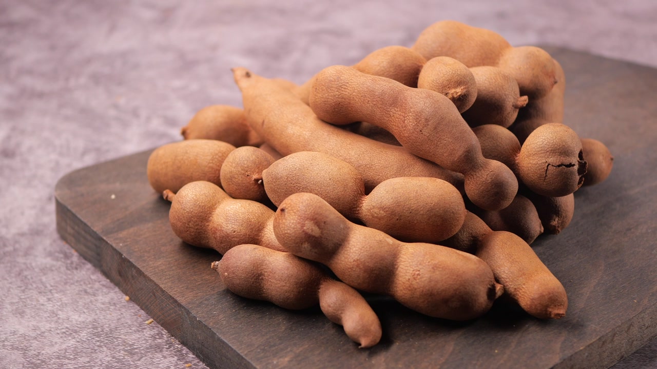 Fresh Tamarind Pods on a Wooden Cutting Board